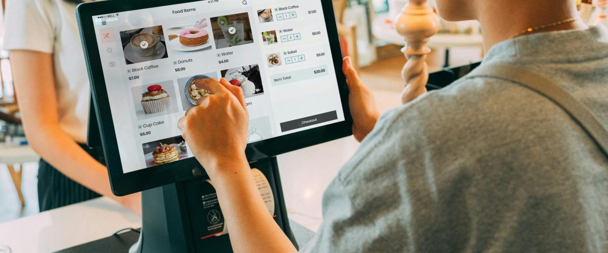A customer using a touch screen system at a cafe counter for modern payment processing.