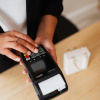 A person's hand using a card payment terminal, illustrating a cashless transaction.